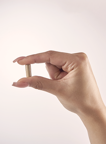 Woman with acrylic nails holding a pill