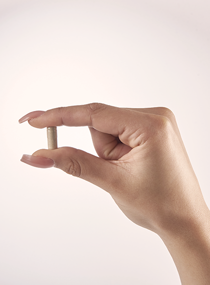 Glow and Grow supplement capsule held in thumb and forefinger