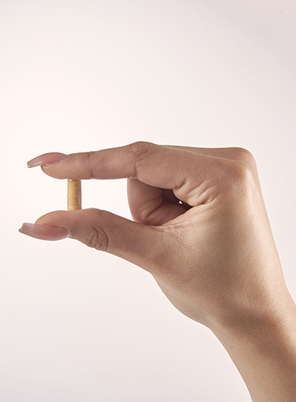 Gut Goodness Vegan supplement capsule held with thumb and forefinger