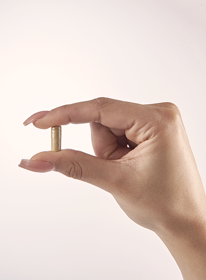 Iron up supplement capsule held with thumb and forefinger