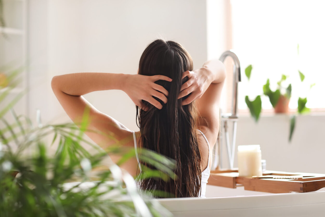 Woman Applying We are Nutrified hair growth oil to hair in bathroom